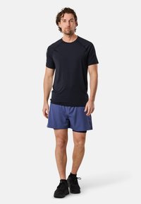 Zwart sportt-shirt met korte mouwen en een ronde hals, gecombineerd met blauwe shorts en zwarte sportschoenen. Eenvoudig ontwerp, lichte stof.