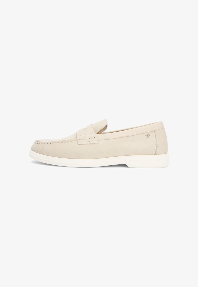 Mocassin en cuir beige à enfiler avec semelle blanche, bout mocassin cousu et petit détail de logo sur le côté, présenté en vue de profil.