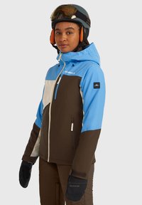 Skijack in blauw, bruin en wit, met een capuchon, ritszakken en zwarte handschoenen. Soepele textuur met een sportief ontwerp.