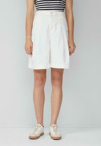 Białe bawełniane szorty o szerokim kroju, z pasem ze szlufkami i bocznymi kieszeniami. W połączeniu z jasnymi trampkami.