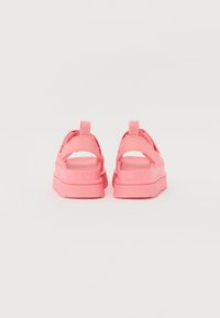 Rosa sandaler med en chunky såle, justerbare stropper og en løkke ved hælen for enkel påkledning. Glatt tekstur og minimalistisk design.
