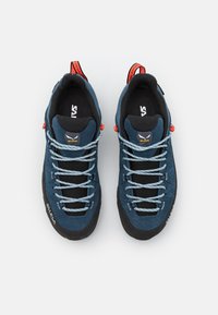 Climbing shoes with dark blue suede upper, black rubber sole, and gray laces. Features red accents and a reinforced toe for durability.