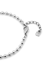 Pulsera de cadena de bola plateada con un cierre de langosta, una cadena de extensión y una pequeña etiqueta marcada con "UNO". Superficie lisa y reflectante con cuentas redondas.