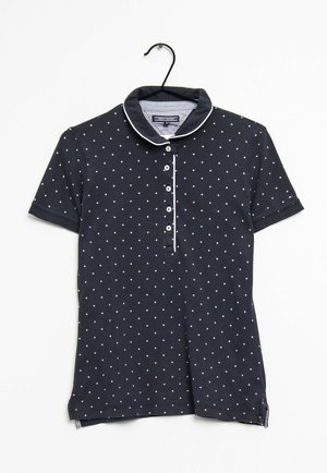 Granatowa koszulka polo z krótkim rękawem, białe kropki, pięć guzików z przodu oraz białe wykończenie kołnierzyka i linii guzików.