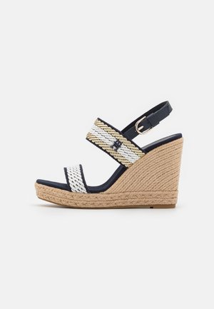 Kile sandal med fletplatform i jute, navyblå og hvide stribede stropper i stof og en justerbar ankelrem med spænde i navy.