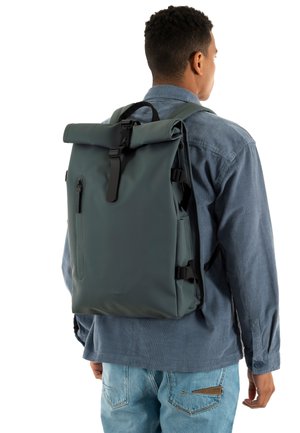 Zaino roll-top in materiale impermeabile grigio scuro. Presenta spallacci regolabili, tasca frontale con zip e design minimalista.