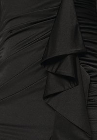 Robe noire avec une texture froncée et des volants superposés, fabriquée à partir d'un tissu lisse et brillant avec une silhouette épurée.