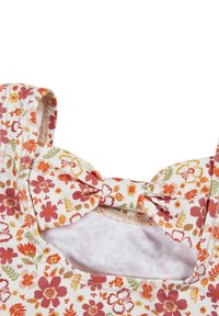 Blusenshirt mit Blumenmuster auf cremigem Hintergrund. Verziert mit einer Schleifenapplikation und breiten Trägern, aus weichem, leichtem Stoff gefertigt.