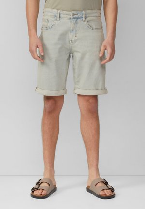 Shorts en denim délavé avec des revers, dotés de poches avant et d'un design classique à cinq poches. Associés à des sandales à glisser brunes.