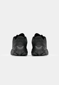 Chaussures de sport noires avec un dessus texturé, un col rembourré et une semelle extérieure robuste. La vue arrière met en avant la conception solide et la forme de la chaussure.