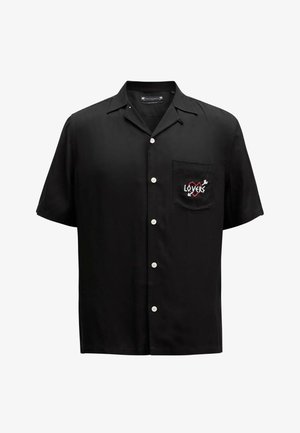 Chemise noire à manches courtes en tissu lisse, dotée d'une poche avec un design brodé "LOVERS" en rouge et blanc, et de boutons blancs.