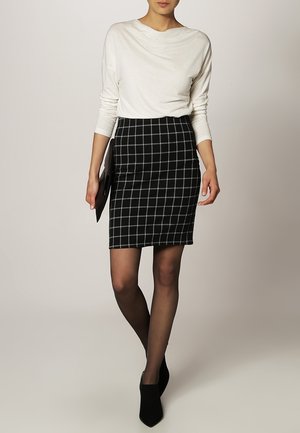 Witte, gewatteerde top met lange mouwen, gecombineerd met een zwart-wit geblokte kokerrok. Zwarte hoge hakken, minimalistisch ontwerp, getailleerde pasvorm.