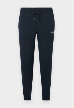 Pantalon de survêtement bleu marine fuselé avec taille élastique, cordon de serrage, chevilles côtelées et petit logo blanc sur la partie supérieure de la cuisse gauche.