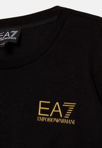 Schwarzes Baumwoll-T-Shirt mit Rundhalsausschnitt. Verfügt über ein gelbes Logo mit dem Text "EA7" und "EMPORIO ARMANI". Weicher Stoff und taillierte Passform.