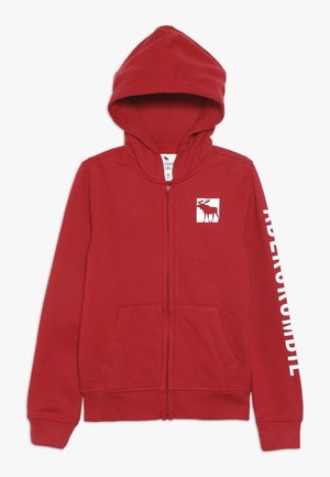 Sudadera con capucha roja con cremallera, hecha de tela suave, que cuenta con un bolsillo tipo canguro, una capucha y un gráfico de alce en el pecho con texto de la marca en blanco en la manga.