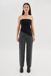 Top nero senza spalline con orlo diagonale, abbinato a pantaloni grigi a righe e stivali neri con tacco spesso alla caviglia. Collana choker metallica semplice.