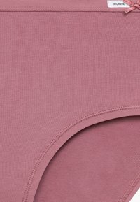 Różowa bawełniana bielizna charakteryzująca się gładką fakturą, elastycznym paskiem w talii oraz małą kokardką blisko pasa.