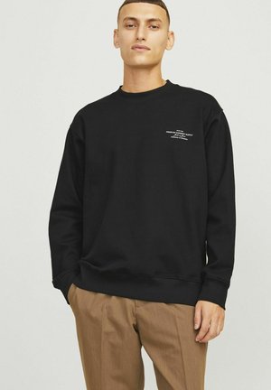 Sudadera negra hecha de una tela suave, con un cuello redondo y un pequeño logo blanco en el pecho. Corte regular con puños de canalé.