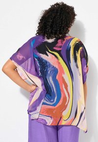 Blusa trasparente con un motivo astratto multicolore a spirale in viola, rosa, giallo e nero. Taglio oversize con maniche ampie.