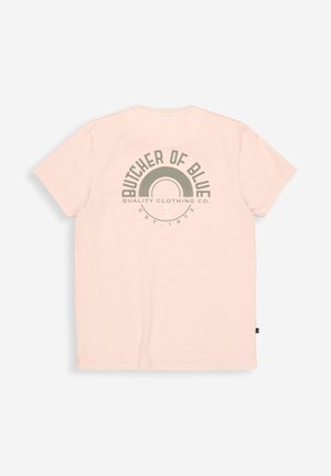 T-shirt rose clair à manches courtes avec un logo gris "Butcher of Blue" et un texte centrés dans le dos, étalé à plat sur un fond blanc.
