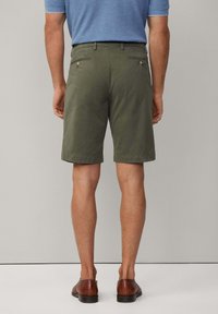 Olivengrønne bomuldsshorts med lige design, to baglommer og diskrete syninger. Båret med brune lædersko.