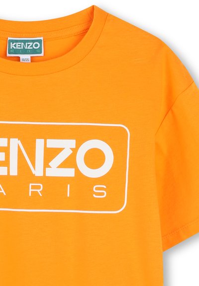 Bright orange cotton T-shirt featuring a white rectangular logo with "KENZO" and "PARIS." Classic crew neck design with short sleeves.