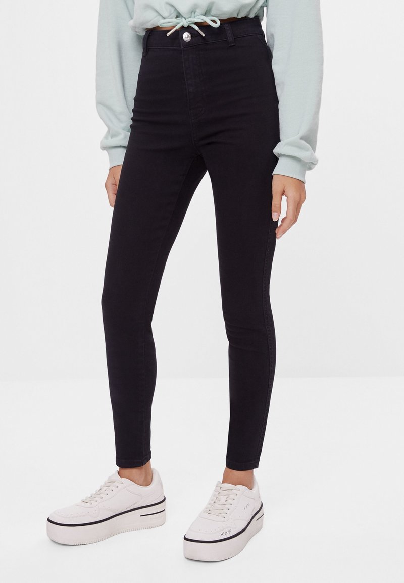 Svarta högmidjade skinny jeans i denim, med knappstängning fram, kontrasterande sömmar och en smal, figurnära silhuett.