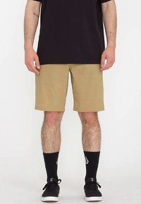 Shorts kaki à hauteur des genoux en tissu texturé et coupe droite, portés avec des chaussettes noires et des chaussures noires, associés à un t-shirt foncé.