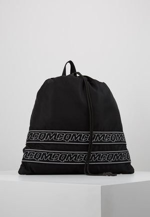 Zaino nero con coulisse con due bande orizzontali bianche con il logo "MCQ" al centro, posizionato su una superficie bianca.