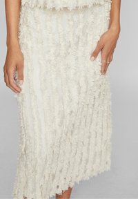 Ivory-hame tekstuuri fringing'iga, millel on kihiline disain, läbipaistva aluskihi ja ainulaadse vertikaalsete joonte mustriga.