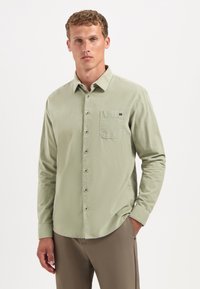 Lichtgroen overhemd met lange mouwen, knopen aan de voorkant, kraag, enkele borstzak en een zachte, getextureerde stof. Gekocht met beige broek.