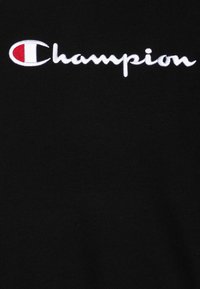 Felpa nera con logo "Champion" ricamato in bianco, con un piccolo accento circolare rosso e bianco sulla lettera "C".