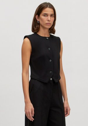 Zwarte mouwloze top met een ronde hals en een sluiting met vijf knopen aan de voorkant. De stof heeft een gladde textuur, een getailleerde fit en een cropped ontwerp.