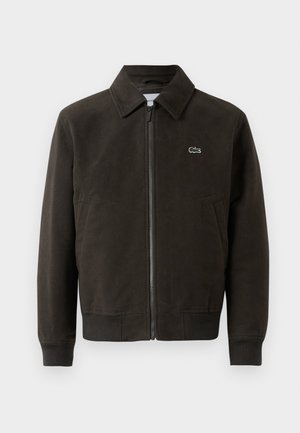 Giacca in suede marrone con colletto, chiusura frontale con zip e polsini a costine. Presenta un piccolo logo verde Lacoste sul lato sinistro del petto.