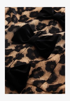 Sort og guld leopard mønstret stof med store fløjlsløjfer. Materialet har et struktureret, vævet mønster, der skaber visuel dybde og kontrast.