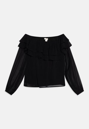 Sort off-shoulder bluse med lagdelte flæser, gennemsigtige lange ærmer og elastisk halsudskæring mod en hvid baggrund.