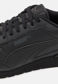 Sneaker in pelle nera con superficie texturizzata, lacci e un logo Puma ben visibile sul lato. Suola in gomma con dettagli minimi.