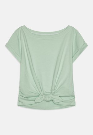Miętowa koszulka z krótkim rękawem o luźnym kroju i zawiązanym detalem na dole. Wykonana z miękkiej, gładkiej tkaniny z okrągłym dekoltem.