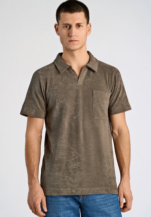 Polo à manches courtes en tissu doux et texturé couleur olive avec un col pointu et une poche poitrine. Design à coupe décontractée.