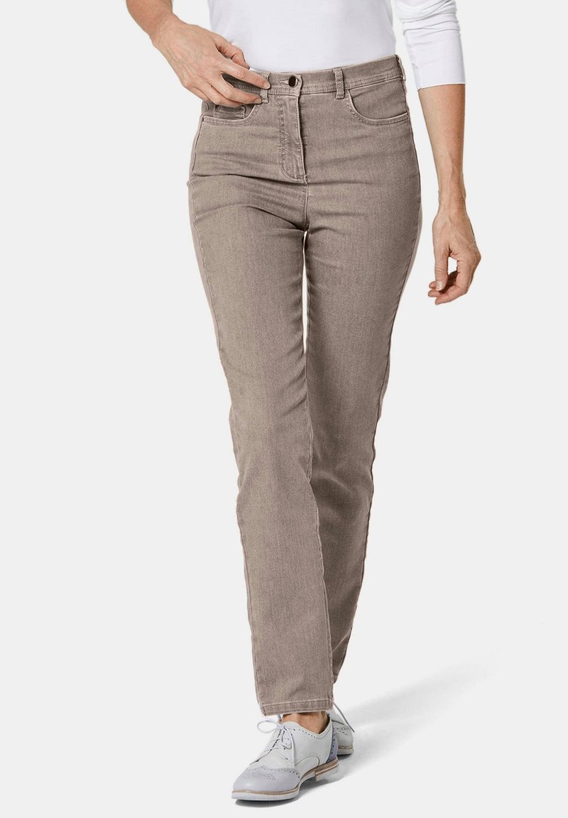 Beige High-Waist-Jeans mit geradem Bein, aus Denim gefertigt. Mit Fronttaschen und einem Reißverschluss. Kombiniert mit hellgrauen Schuhen.