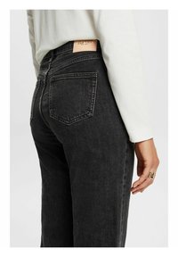 Czarne dżinsy denimowe z pięcioma kieszeniami, skórzaną metką z tyłu i prostym krojem nogawki. Szwy ozdobne i miękka tekstura.