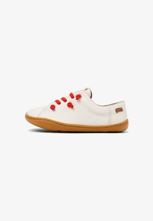 Vita lädersneakers med röda snören, rund tå och beige gummisula. Har en liten beige etikett på hälen. Slät textur.