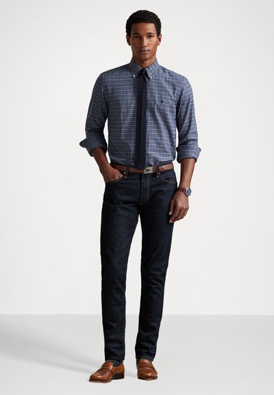 Knapp-ned rutete skjorte i marineblå og hvit, kombinert med mørkeblå jeans. Brun lærbelte og loafers. Lekkert, men uformelt utseende.
