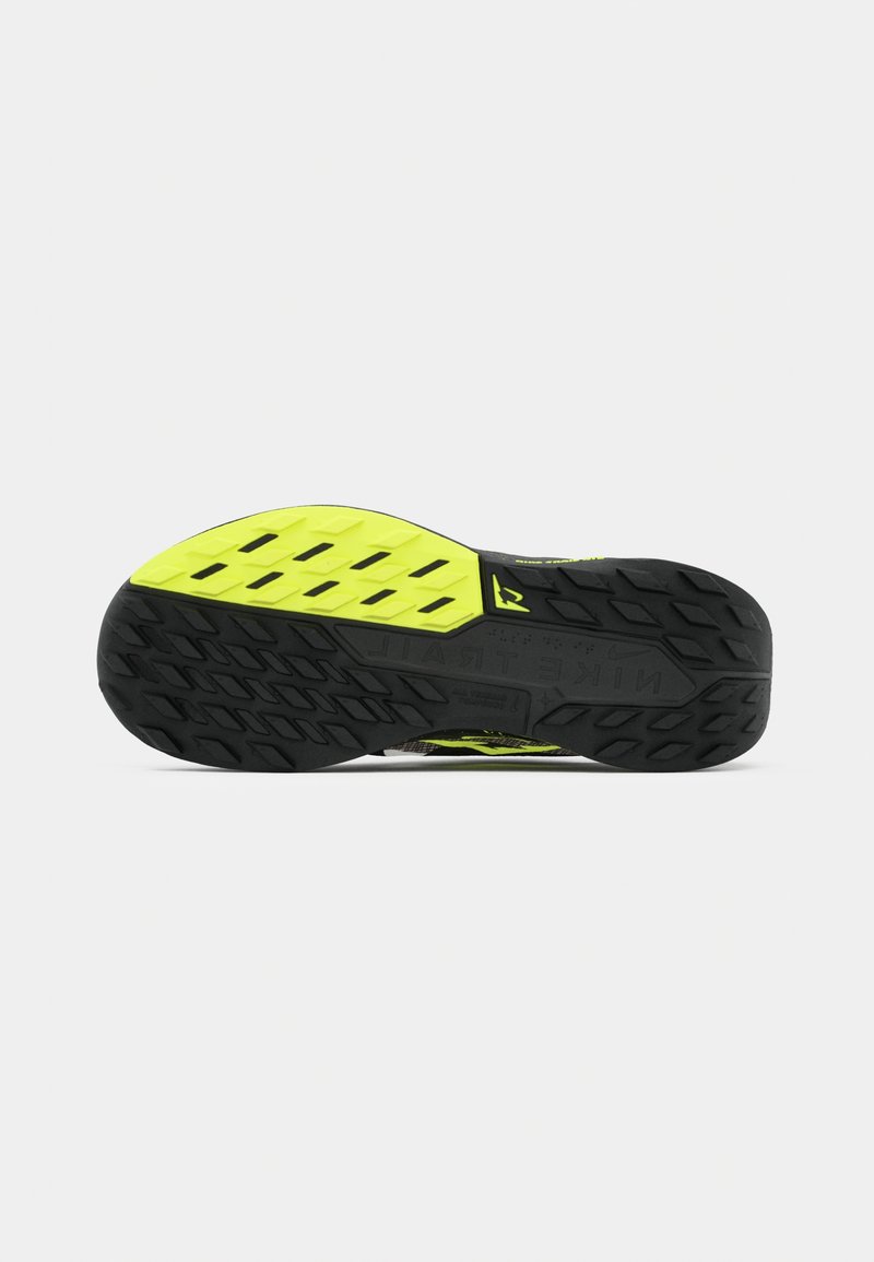 Suela de zapatilla negra con una sección amarilla prominente. Presenta patrones de agarre texturizados y un diseño de banda de rodadura multidireccional.