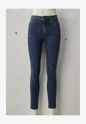 Plānas džinsa bikses tumši zilā krāsā, ar augstu jostasvietu un piegulošu formu, tām ir priekšējās kabatas, rāvējslēdzēja aizdare un viegli izbalējusi auduma tekstūra uz augšstilbiem.