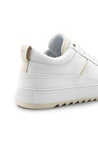Witte leren sneaker met contrasterende beige accenten, gemarmerde rubberen zool, laag ontwerp en logo detail op de hiel.