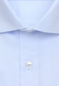 Jasnoniebieska koszula z kołnierzykiem wykonana z teksturowanej tkaniny, z zapięciem na guziki o czterech otworach oraz starannym szyciem wzdłuż krawędzi.