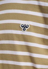 Gestreiftes Baumwoll-T-Shirt in Olivgrün und Weiß, ausgestattet mit einem kleinen Bienen-Patch mit marineblauen Details auf der Brust. Glatte Textur.