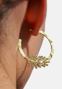 Boucle d'oreille en or avec une finition texturée et un accent de design en forme de feuille, rehaussée de cristaux blancs et d'une pierre centrale.