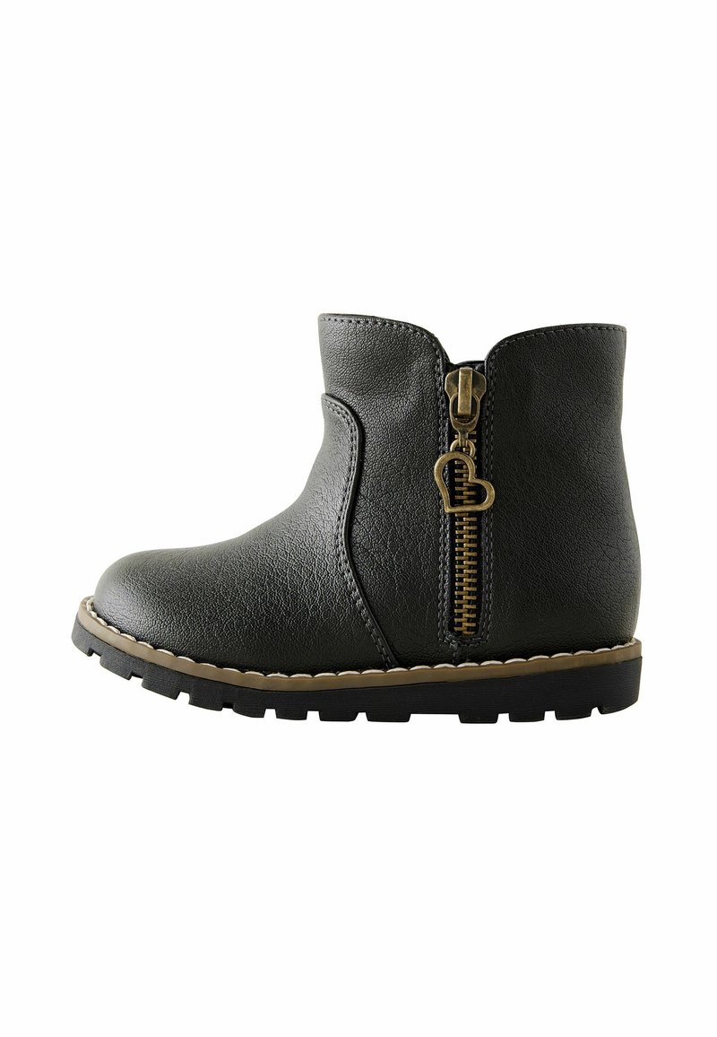 Bottine en cuir noir avec fermeture éclair latérale dotée d'une tirette en forme de cœur et semelle épaisse à crampons avec surpiqûres beiges.